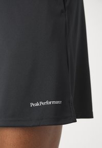 Fekete sportos rövidnadrág sima, tartós anyagból, a szegés közelében található fehér "PeakPerformance" logóval. Egyszerű dizájn, letisztult vonalakkal.