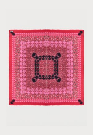 Červený a růžový čtvercový šátek s několika řadami vzorů lebek s květinovými detaily a většími černými lebkami v každém rohu.