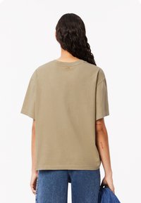 Camiseta de manga corta de color verde oliva en algodón, con cuello redondo y un ajuste relajado. Diseño liso sin patrones ni acentos visibles.