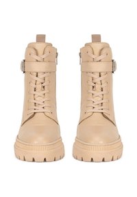 Béžové kožené kotníkové boty s šněrováním v přední části, kovovou sponou a silnou gumovou podrážkou s texturovaným vzorem. 
