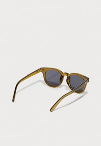 Tortoiseshell sunglasses with grey lenses. Rounded frame, smooth texture, and slender arms. Features a small logo on the inner side.