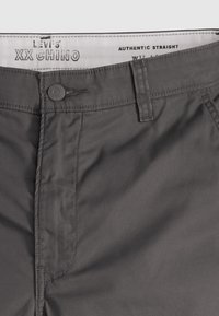 Levi's XX Chino-housut tummanharmaana, suoran lahkeen muotoilulla, etupainikkeella suljettuna ja hienovaraisilla ompeluyksityiskohdilla.