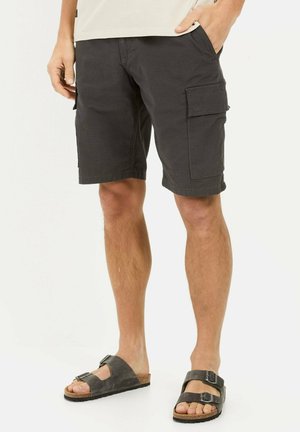 Cargoshorts in donkergrijze stof met een gestructureerde afwerking, voorzien van zijzakken en een relaxte pasvorm. Dit is gecombineerd met donkere, verstelbare sandalen.