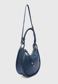 Marineblauwe leren schoudertas met een ronde vorm, voorzien van een lange schouderriem en goudkleurige hardware. Ritssluiting en subtiele merkdetails.