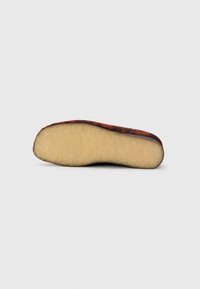 La suola della scarpa presenta una forma arrotondata con una parte superiore in testo marrone e un morbido rivestimento in pile beige chiaro per comfort e supporto.