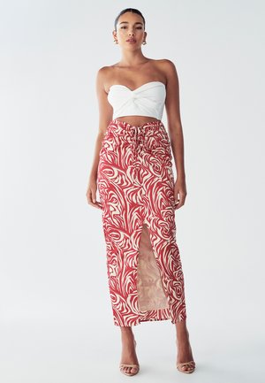 Hvid stropløs top og en rød mønstret maxi-nederdel med et off-white svunget design, der har en forkert slids og snoreliv.