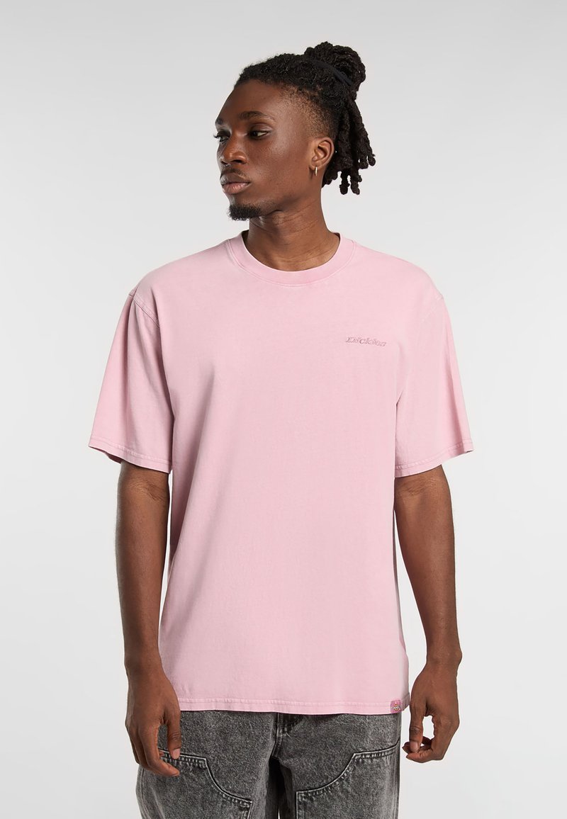 Rosa kortärmad t-shirt i bomull med runda halskant och liten logotypdetalj på bröstet. Bärs med gråbyxor.