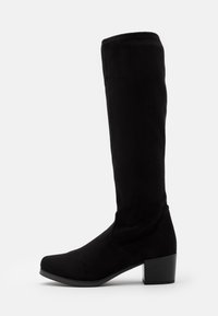 Bottes noires montantes en daim doux, avec un bout arrondi et un talon bloc. Le design est épuré avec des détails de couture minimalistes.