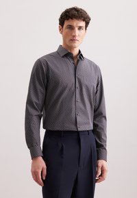 Camicia a maniche lunghe a fantasia di colore blu scuro con motivi geometrici in rosso e bianco. Presenta un colletto classico e chiusura con bottoni.