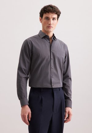 Camicia a maniche lunghe a fantasia di colore blu scuro con motivi geometrici in rosso e bianco. Presenta un colletto classico e chiusura con bottoni.