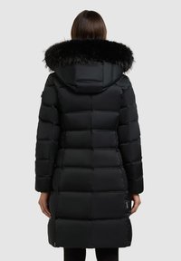 Svart dunjacka med quiltad design, utrustad med en avtagbar huva i svart fuskpäls. Långa ärmar och en midjelång skärning, praktisk för kallt väder.