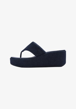 Donkere denim platform slippers met een brede teenband, afgeronde randen en een gestructureerd oppervlak. Heeft een lage sleehak voor extra hoogte.