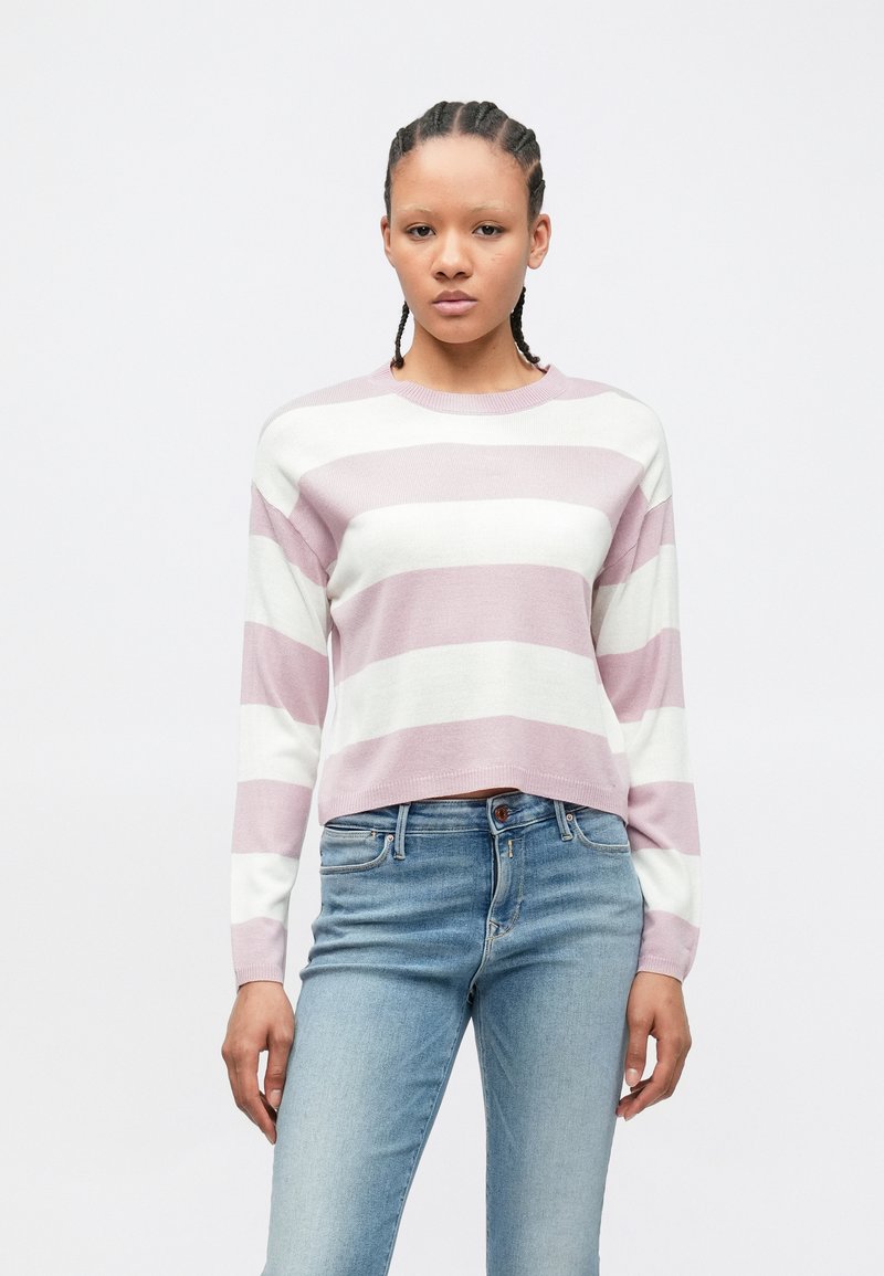 Pull court rayé rose pâle et blanc à manches longues, en tissu tricoté. Porté avec un jean en denim bleu.