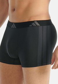 Čierne boxerky s hladkým povrchom, so tónovými pruhmi a čiernym pásom s jemným dizajnom loga.