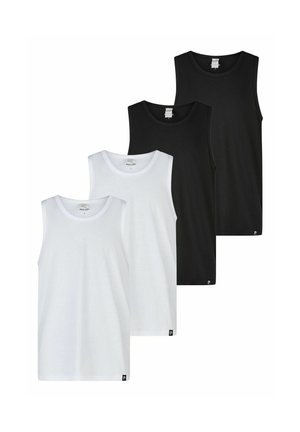 Mann trägt ein schlichtes schwarzes ärmelloses Tanktop und schwarze enganliegende Shorts, steht mit den Armen hinter dem Rücken vor hellem Hintergrund.
