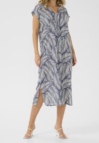 Robe midi à manches courtes en bleu marine avec un motif de feuilles blanches, dotée d'un décolleté en V et d'échancrures sur les côtés pour faciliter le mouvement. Tissu doux et léger.