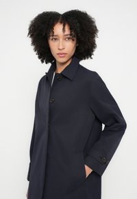 Μπλε παλτό από απαλό ύφασμα με γιακά, κουμπιά μπροστά και πλαϊνές τσέπες. Διαθέτει εφαρμοστή γραμμή και καθαρό σχεδιασμό.