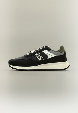 Schwarz-weißer Jack & Jones Sneaker mit Schnürdesign, weißer Sohle und grünlich-grauem Innenfutter auf neutralem Hintergrund.
