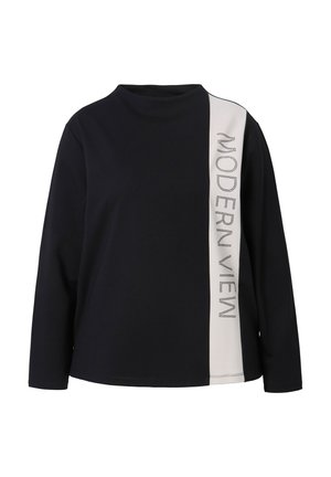 Top negro de manga larga con un panel blanco que lleva el texto "MODERN VIEW" en tachuelas plateadas. La tela parece suave y tiene un corte relajado.