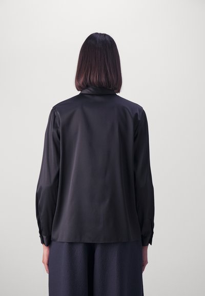 Chemise en satin noire à manches longues avec une texture lisse, dotée d'un col et de poignets à boutons, vue de dos.