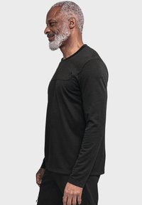 Schwarz Langarmshirt aus weichem Material mit Rundhalsausschnitt. Verfügt über ein flaches Nahtdesign an den Schultern und ein dezentes Logo-Detail.