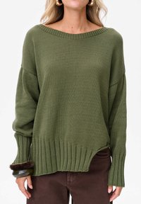 Oliwkowy sweter dziany z szerokim dekoltem w łódkę, ściągaczem u dołu i długimi rękawami. Posiada zaszewkę po boku oraz fakturowany materiał.