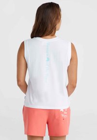 Vit ärmlös topp med ljusblå text "Women of the Wave" p�å baksidan. Matchat med korallfärgade shorts med vit märkning på fickan.