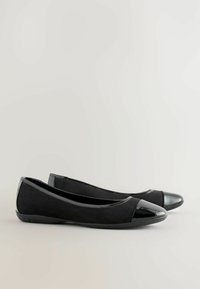 Svarta ballerinaskor i mocka med en blänkande tå i lackläder. Har en låg profil design med en mjuk textur och flexibel sula.
