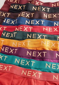 Stack di biancheria intima da uomo in vari colori con ampie fasce elastiche in vita etichettate con "NEXT" a lettere contrastanti.