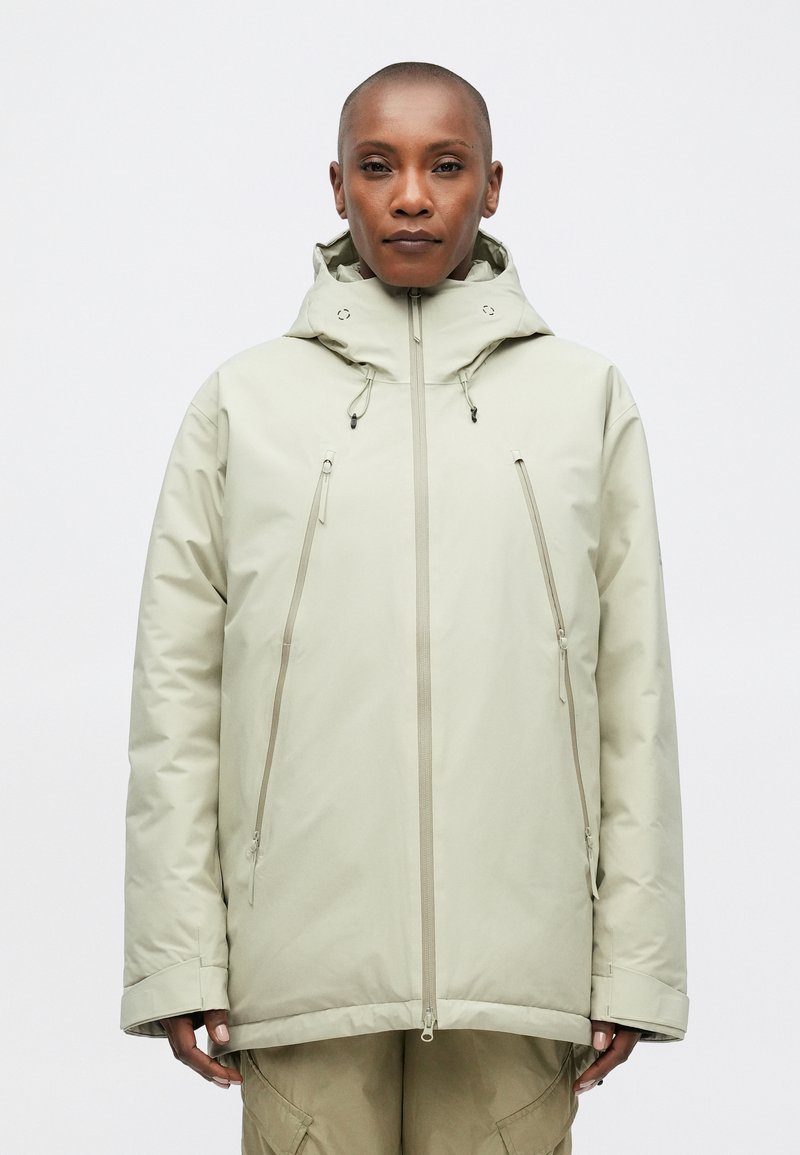 Helle beigefarbene isolierte Jacke mit hohem Kragen, verstellbarem Kapuze und Reißverschlusstaschen an der Vorderseite. Glatte Textur und minimalistisches Design.