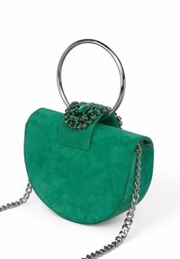 Bolso de ante verde con forma redondeada, asa de anillo plateada, detalle de cierre con joyas y una correa de cadena metálica. Superficie texturizada.