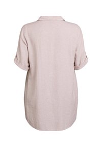 Camicia di lino rosa chiaro con colletto e maniche corte arrotolate; presenta una vestibilità ampia e rilassata e un tessuto semplice e strutturato.