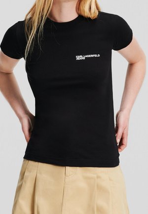 Camiseta negra ajustada de algodón elástico. Presenta un logo blanco "KARL LAGERFELD JEANS" en el área del pecho izquierdo. Mangas cortas.