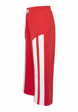 Pantaloni sportivi rossi a gamba larga con strisce verticali bianche e vita elastica con coulisse bianca.