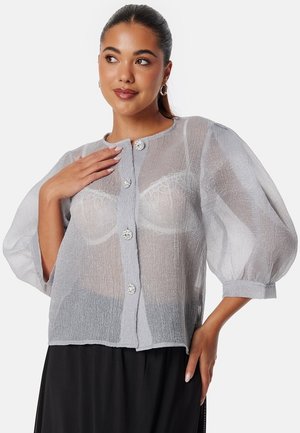 Sheer gray blouse with puffed sleeves, featuring a round neckline and decorative buttons. Textured fabric offers a light, airy appearance.
