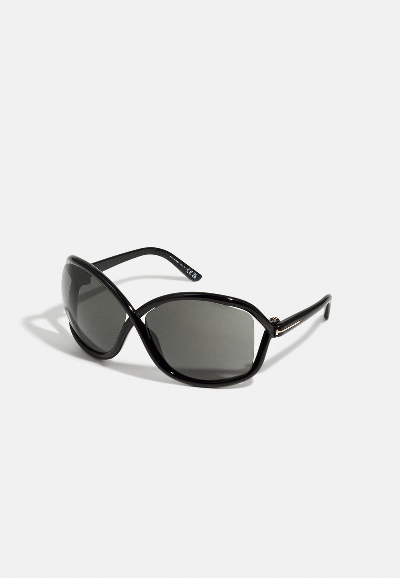 Occhiali da sole neri con una montatura larga e angolare e lenti scure. Presentano tempie curve e un sottile accento metallico vicino agli snodi.