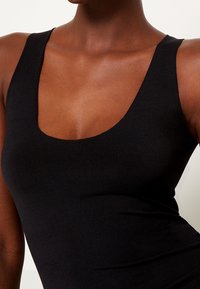 Schwarzes ärmelloses Oberteil mit einem Rundhalsausschnitt, aus glattem, dehnbarem Stoff, mit einer figurnahen Silhouette und leichtem Glanz.