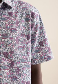 Camicia con un motivo floreale nei colori rosa, blu e bianco; maniche corte e colletto; tessuto leggero con dettagli di design intricati.