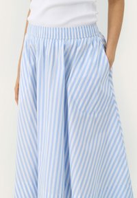 Light blue and white striped, ankle-length skirt with an elastic waistband and side pockets. Made from a soft, breathable fabric.