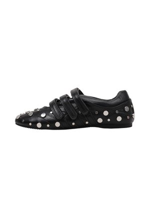 Zapato plano de cuero negro con tres tiras de velcro y tachuelas redondas plateadas de diferentes tamaños en la parte superior y los lados.