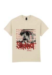 Beżowa bawełniana koszulka z krótkim rękawem, z graficznym wzorem zawierającym czarno-białe zdjęcie, czerwony tekst i efekty rozprysków; wyraźnie widoczny napis "Slipknot".