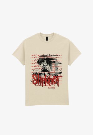 Béžové bavlněné tričko s krátkým rukávem s grafickým motivem obsahujícím černobílý obrázek, červený text a efekty stříkanců; výrazně zobrazen nápis „Slipknot“.