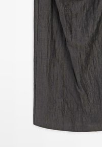 Dunkelgrauer, zerknitterter Stoff mit vertikalen Falten und einem leicht gebogenen Saum vor einem schlichten weißen Hintergrund.