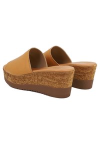 Sandali con zeppa in pelle marrone con una piattaforma in sughero. Design aperto sul retro, parte superiore liscia e suola in gomma per una buona aderenza.