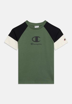 T-shirt vert à manches courtes avec des manches en bloc de couleur noir et blanc, avec le logo Champion et un texte noir sur la poitrine et la manche.