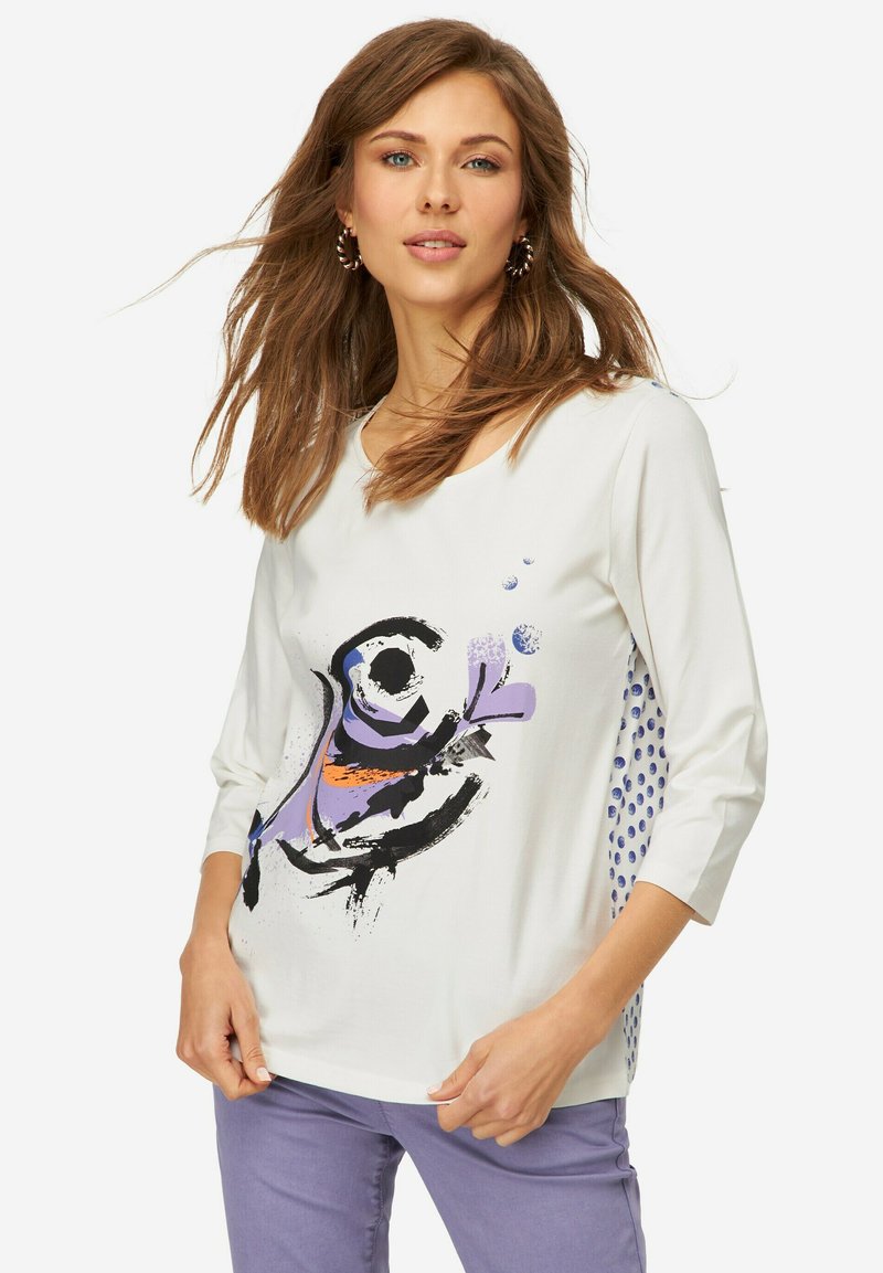 Weißes Langarmshirt mit einem bunten abstrakten Design. Akzente in Lila und Orange, mit blauen Punkten an den Seiten.