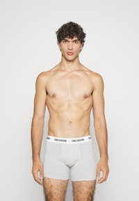 Graue Boxershorts mit einer eng anliegenden Passform, gefertigt aus weichem Stoff. Der Bündchen zeigt ein schwarzes Logo: "ONLY & SONS." Keine weiteren Muster oder Details.