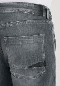 Jeans in denim grigio con una finitura testurizzata, tasca posteriore con una flap curvata e una patch in pelle nera sul cinturino.