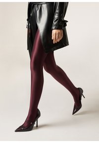 Collants bordeaux associés à un manteau en cuir noir, présentant une texture lisse et une coupe ajustée, soulignés par des escarpins noirs brillants.