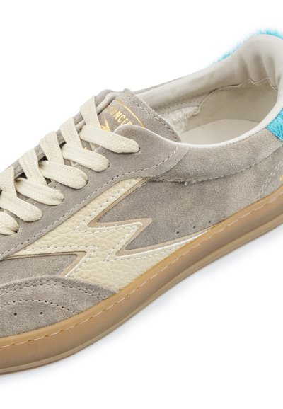 Baskets en daim beige avec un éclair crème, des lacets blanc cassé, un languette de talon bleue et une semelle en caoutchouc marron clair.